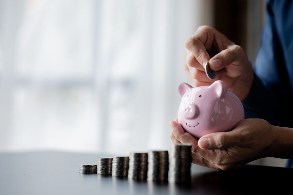 A businessman holding a coin in a piggy bank. Placing coins in a row from low to high.