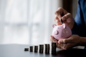A businessman holding a coin in a piggy bank. Placing coins in a row from low to high.