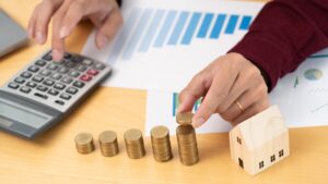Property investment and house mortgage financial concept, hand of a businessman who is stacking coin